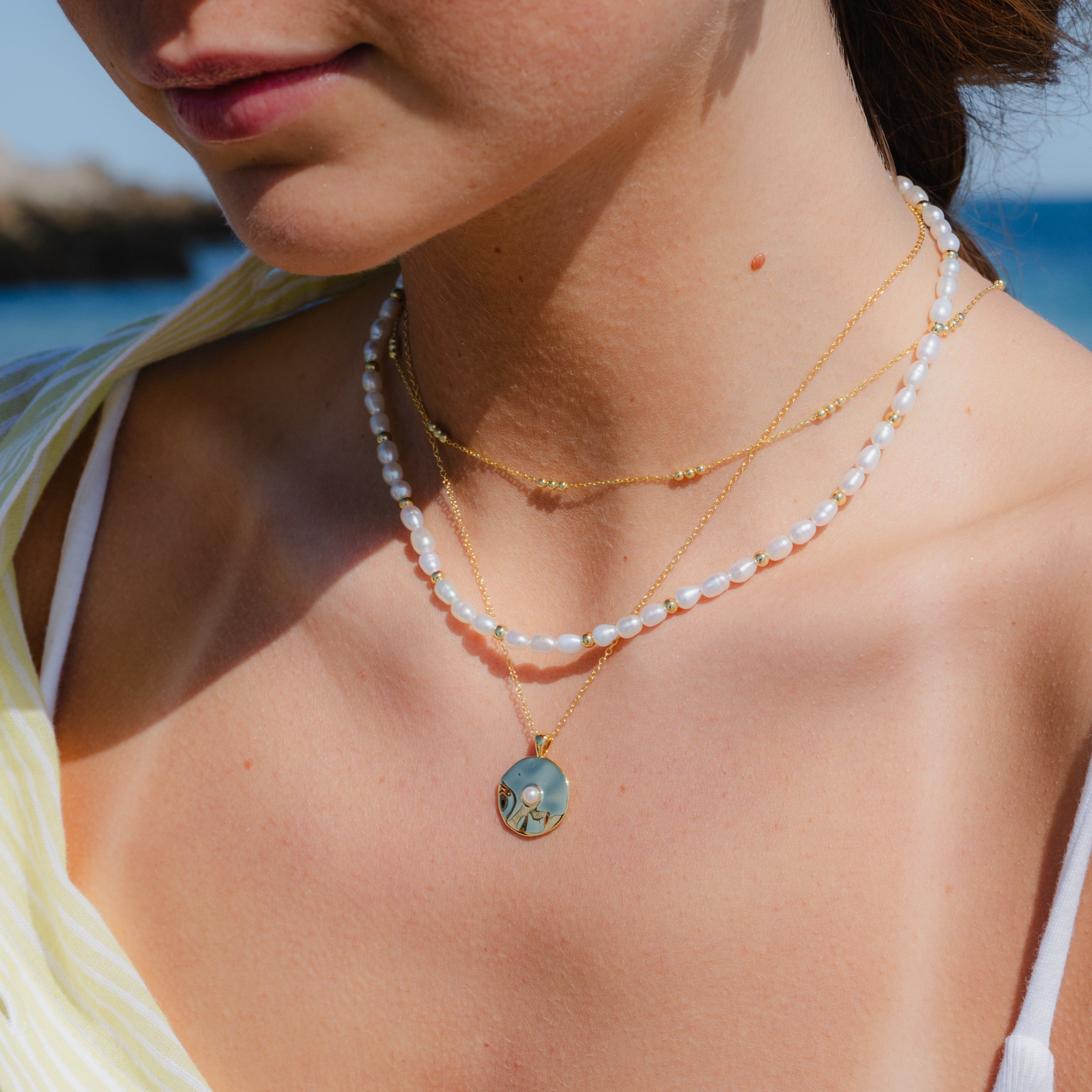 Dainty trio bead gold necklace layered with other necklaces on model

