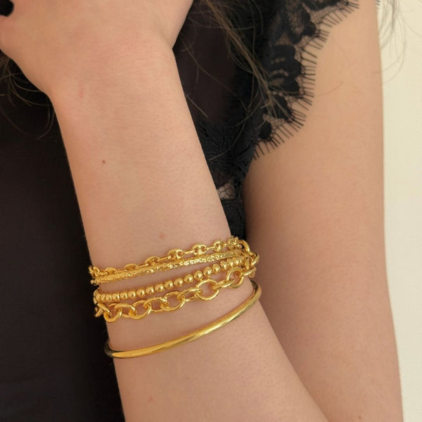 Gold chain bracelets on a wrist with a blurred background