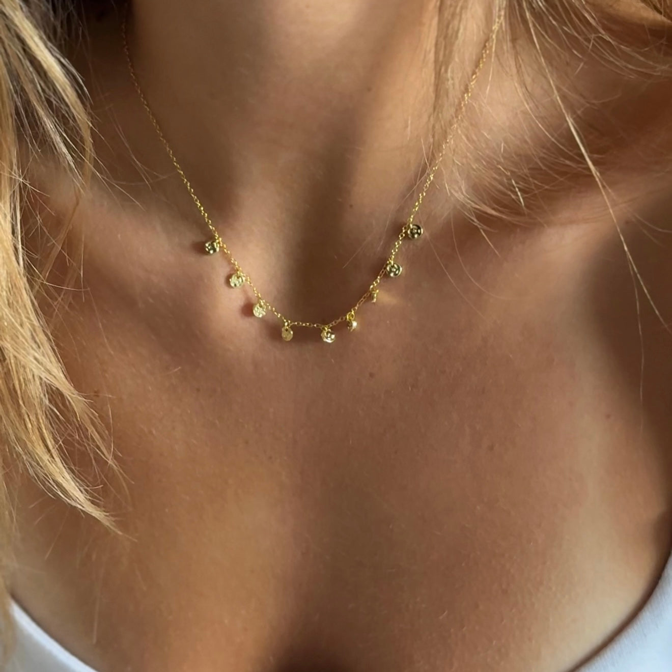 Gold necklace with small pendants on a person's neck