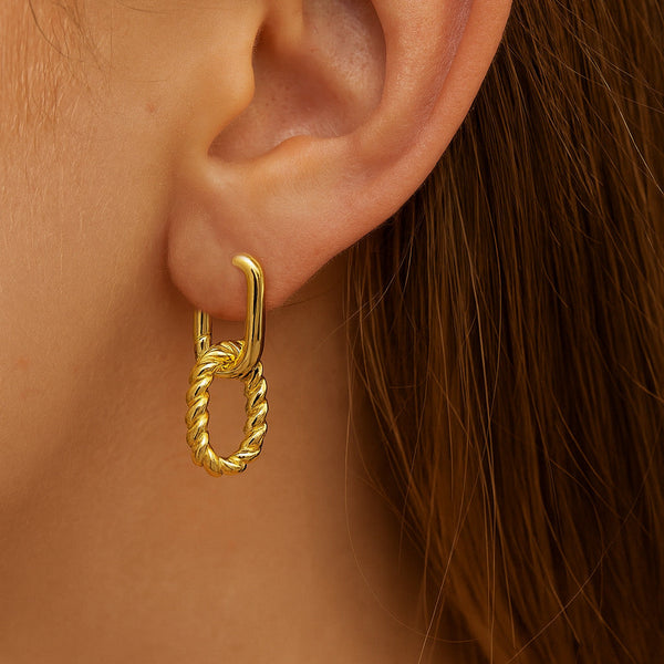 Gold hoop earring worn by a person with brown hair.