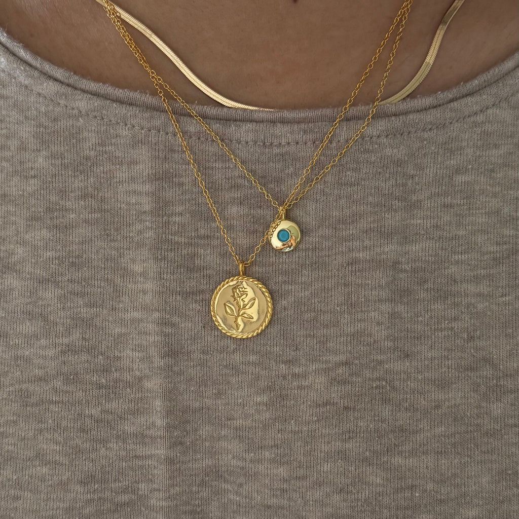 Gold necklace with turquoise pendant styled for a pop of color

