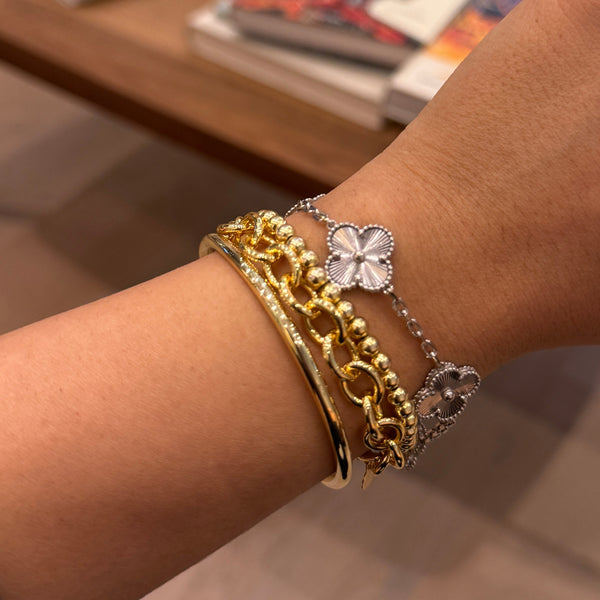 Hand wearing multiple gold bracelets with a blurred background