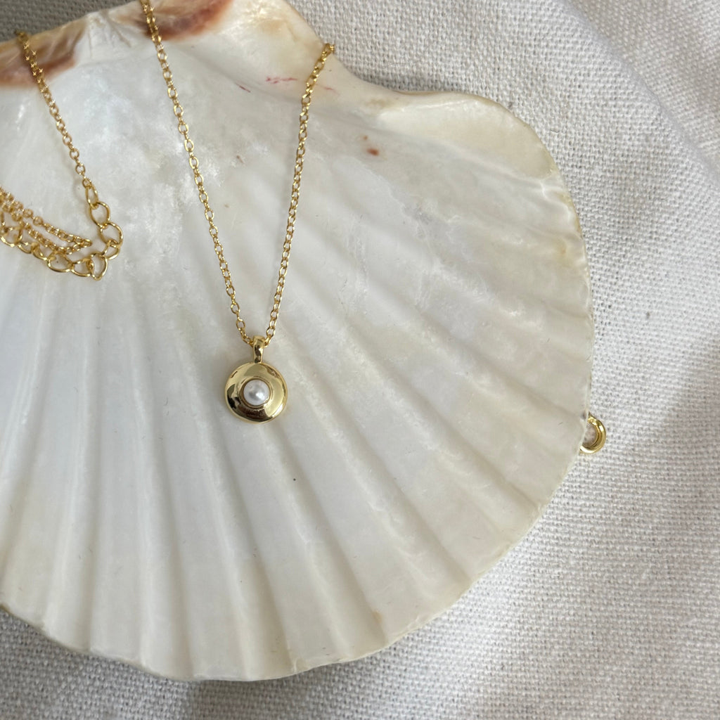 Gold necklace featuring small round pearl pendant

