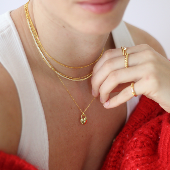 Close-up of a person wearing gold jewelry including a necklace, ring, and earrings.