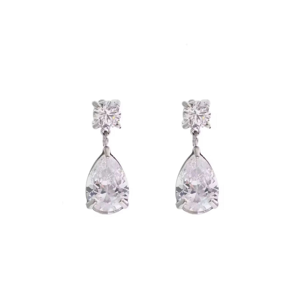 A pair of silver-tone drop earrings featuring a small round-cut clear gemstone in a four-prong setting above a larger pear-cut clear gemstone, shown on a plain white background.