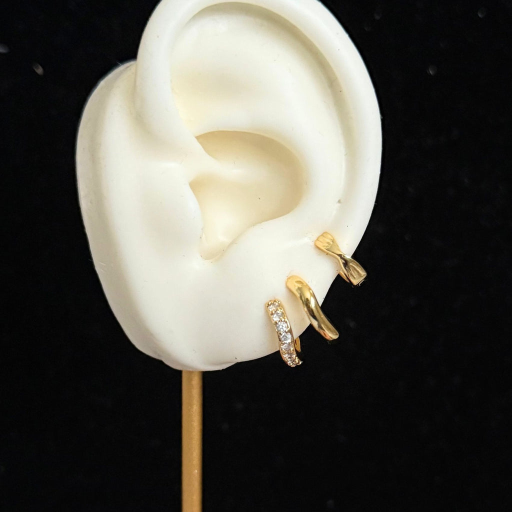 Gold slim wave huggie earrings worn by model, minimalist and modern design shown on ear